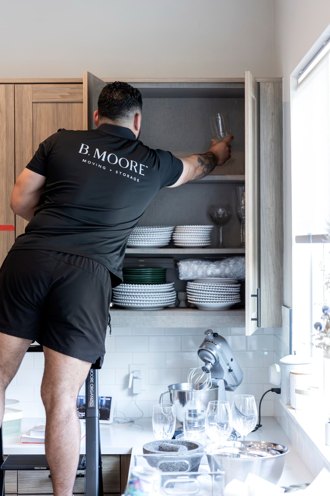 A B. Moore Moving crew member carefully placing stemware and dishware into a client's cabinet