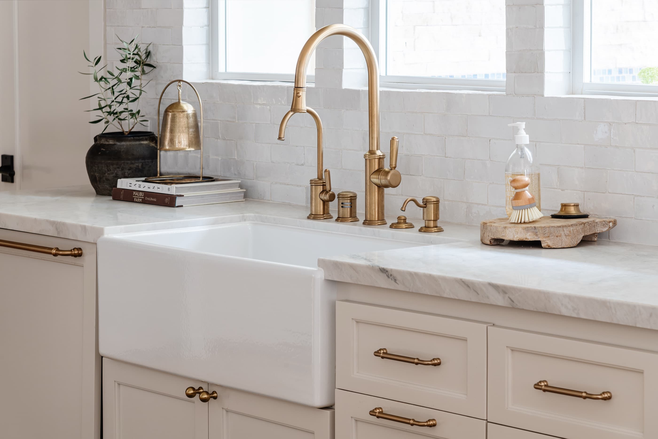 A farmhouse sink and brass fixtures installed in a finished Austin kitchen